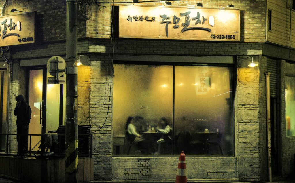 student practicing Korean speaking in Seoul cafe, warm lighting, realistic high quality photo